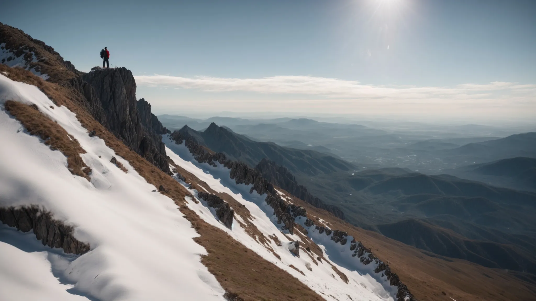 a person standing on the summit of a mountain, looking out towards a clear path ahead.