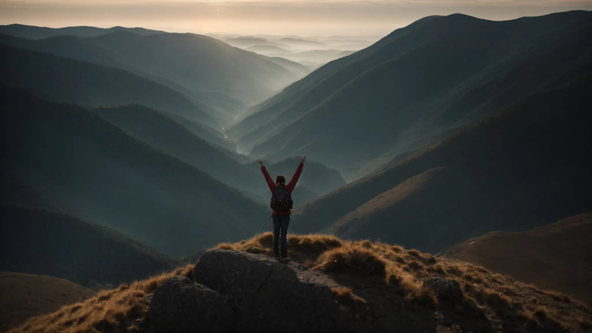 a person standing on top of a mountain, arms outstretched, facing the sun rising over the horizon.